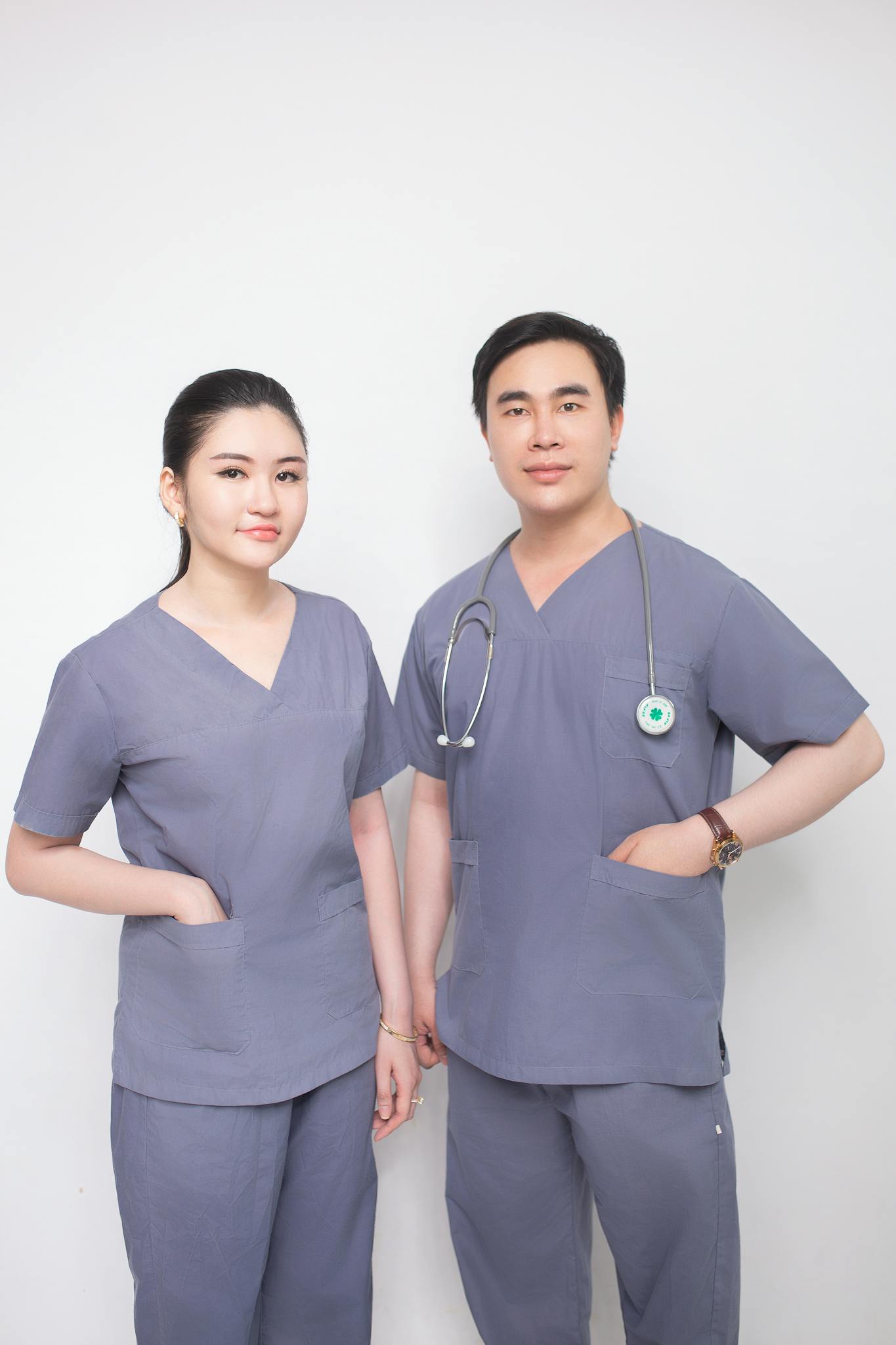 Male and female healthcare professionals in grey scrubs with a stethoscope.