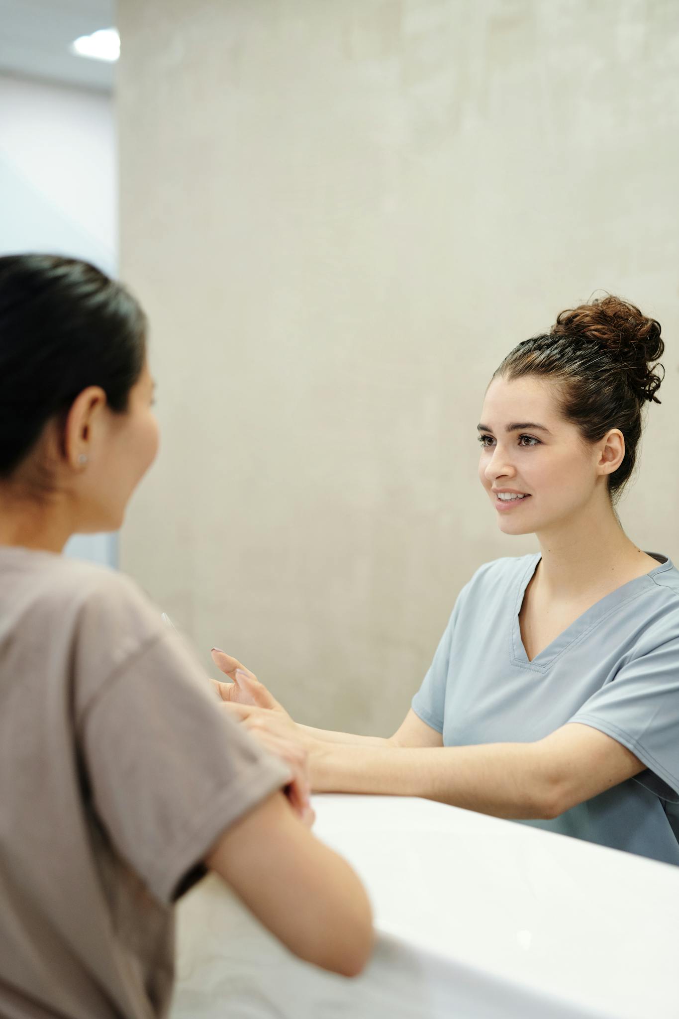Nurse in conversation with patient at a medical reception desk, emphasizing care and support.